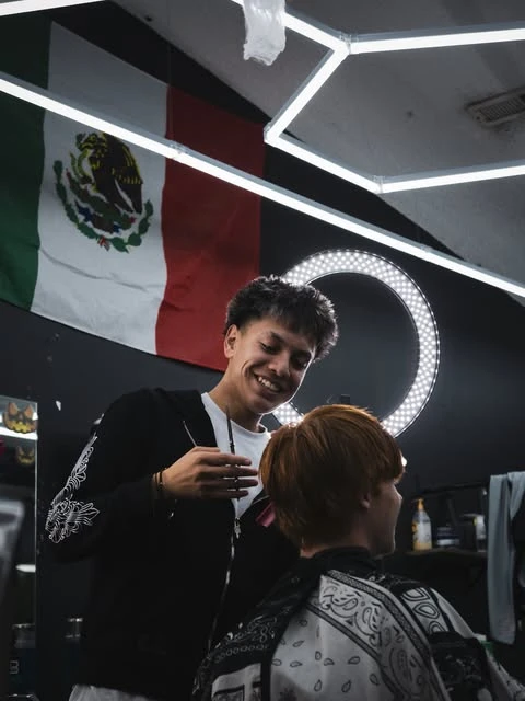 A barber giving a client a cut at West Coast Barbershop